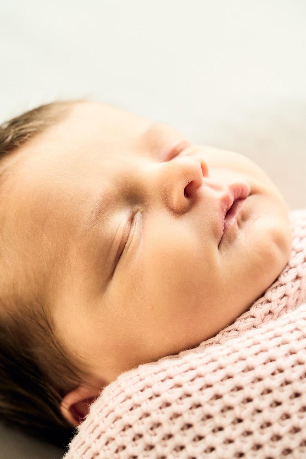 Close portrait of a newborn asleep on a pink knitted blanket