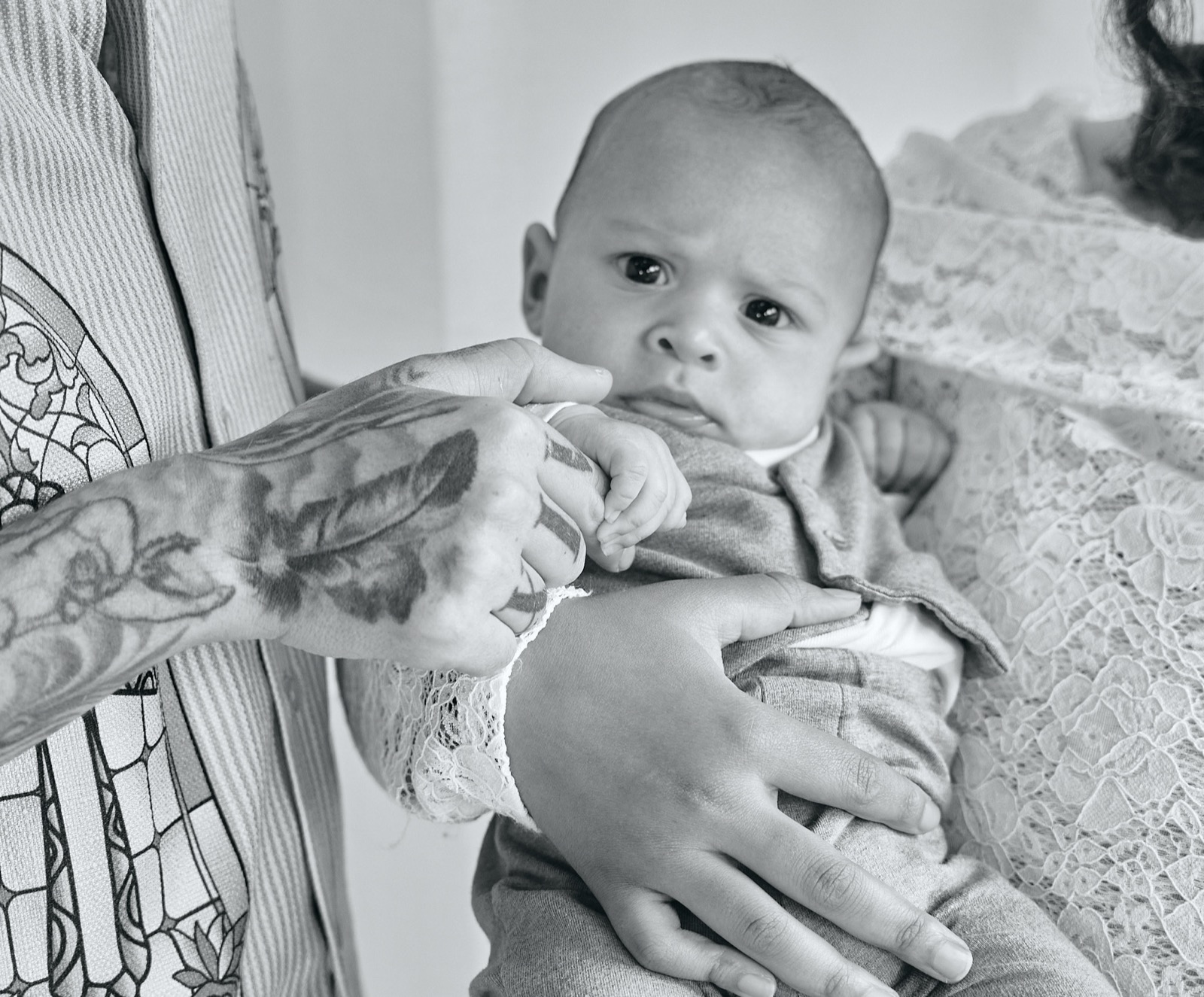 Newborn held in dad's tattooed arms, black and white