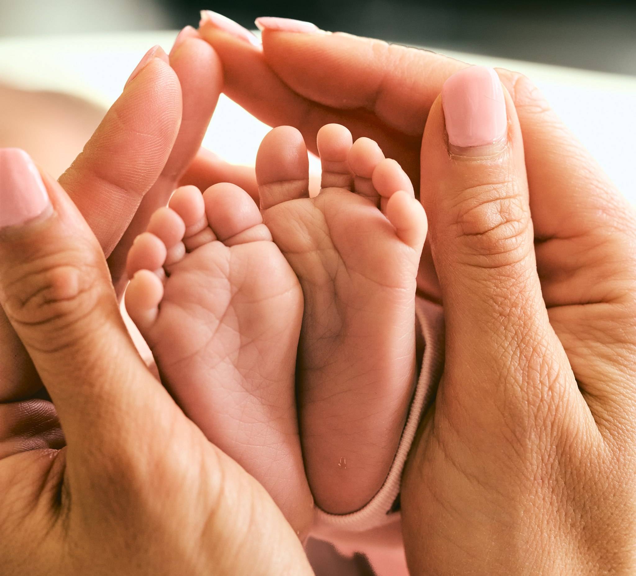 Newborn feet held gently in his parents' hands, close-up in-home newborn photography Melbourne