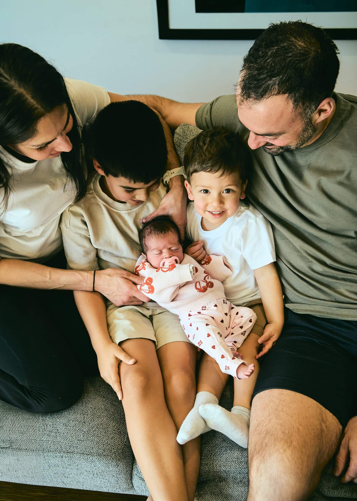 A family cuddled together on the couch around their newborn baby, in-home family session South-East Melbourne
